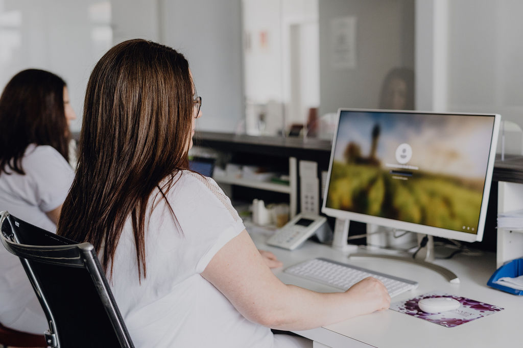 Bildschirm und Mitarbeiterin am Empfang